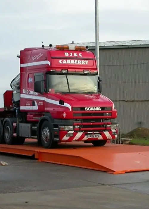 Báscula camionera de plataforma en funcionamiento, utilizada para pesar vehículos grandes y camiones con carga pesada en un entorno industrial, garantizando mediciones precisas y cumplimiento de normativas.